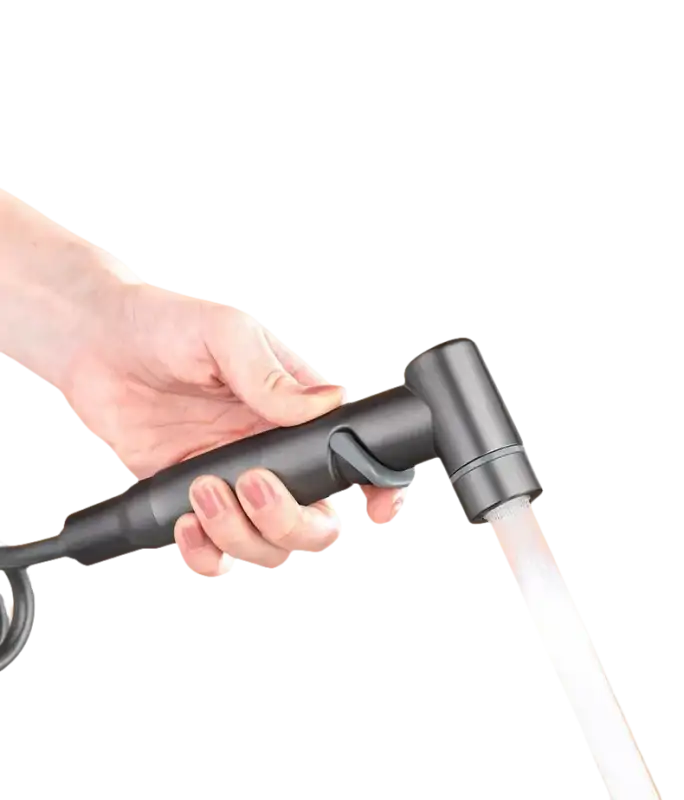 Hand holding a gray bidet sprayer with water flowing.