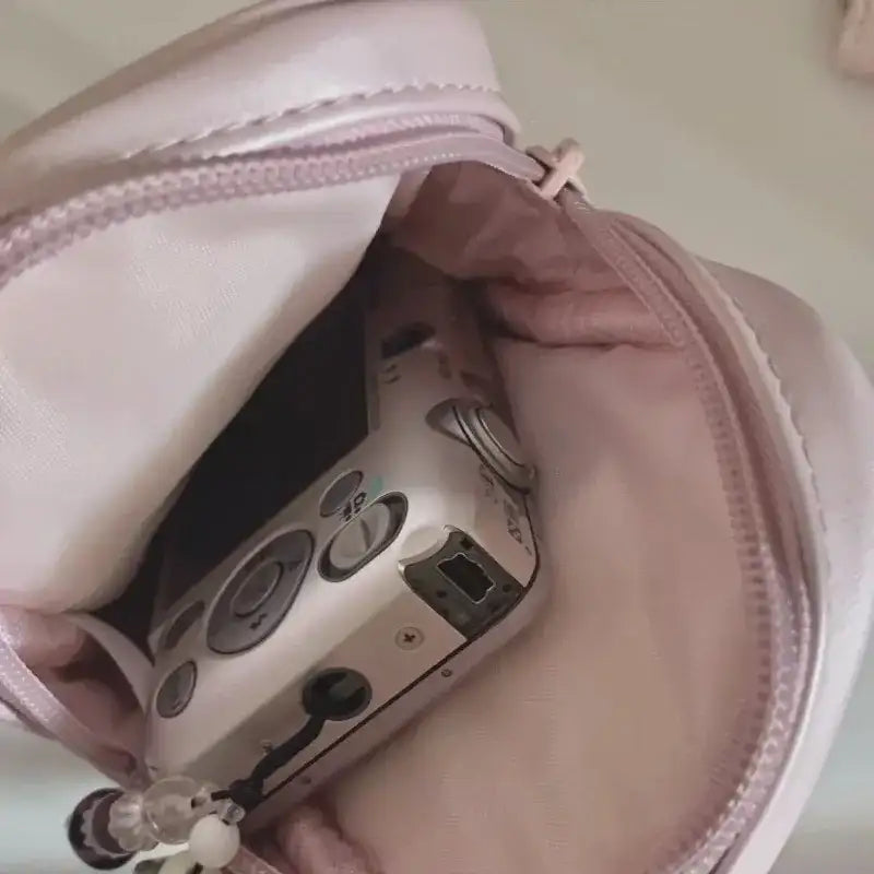 Pink purse containing a silver camera.