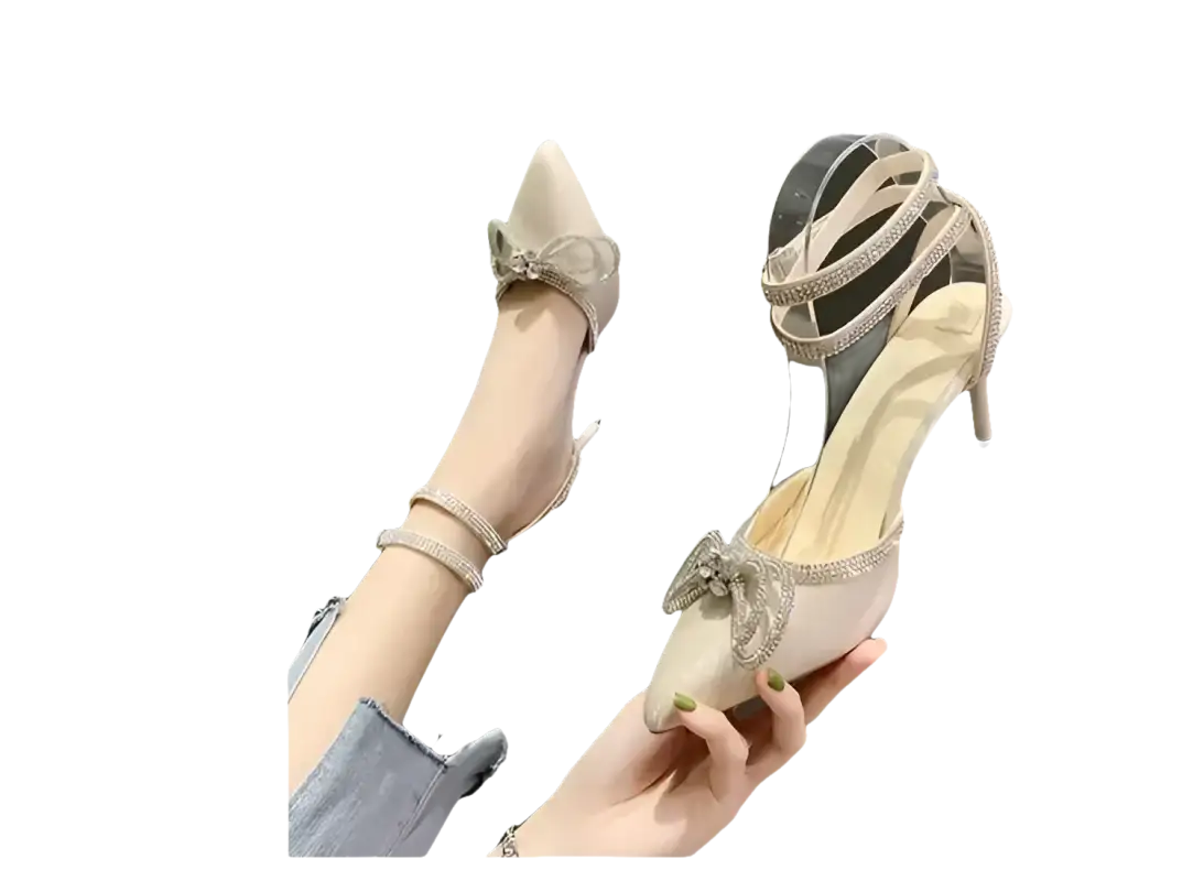Beige high-heeled shoes with rhinestone bows and ankle straps.