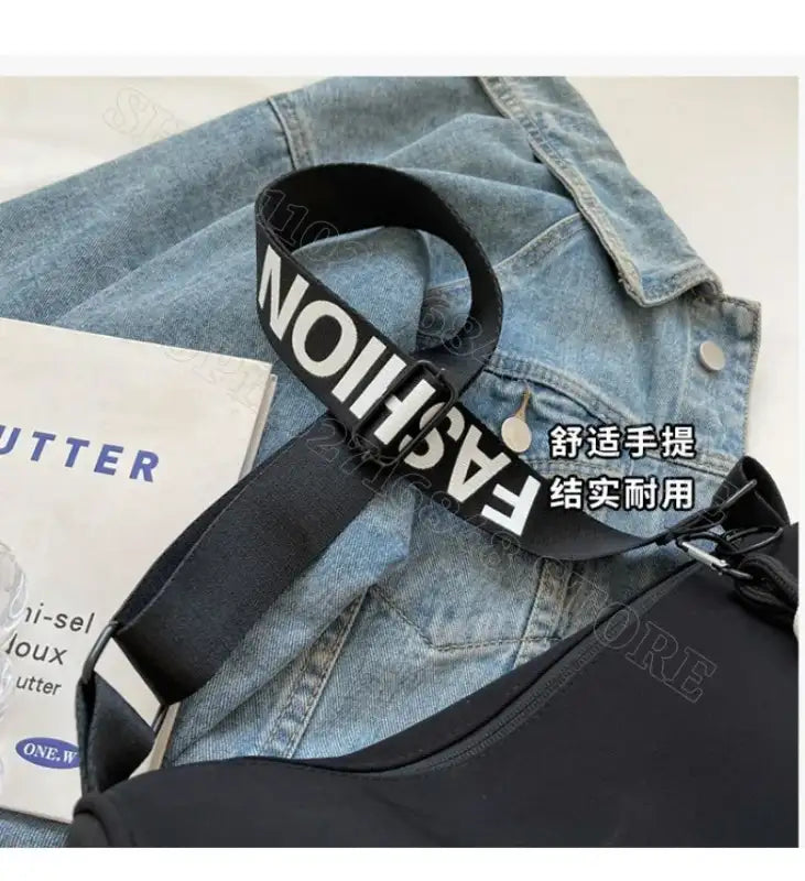 Black shoulder bag with ’FASHION’ strap.