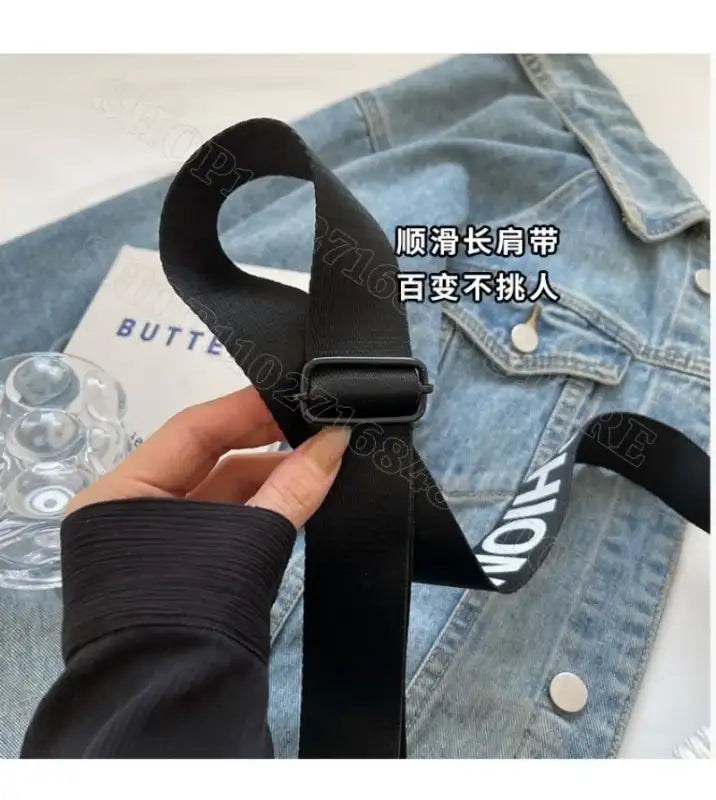 Black bag strap with metal adjuster.