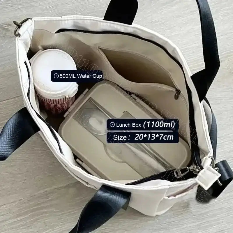 Open tote bag with lunch box and water cup.