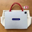 White canvas tote with red handles.