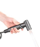 Hand holding a gray bidet sprayer with water flowing.