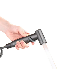 Hand holding a gray bidet sprayer with water flowing.