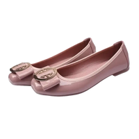 Pair of pink patent leather ballet flats with bow and gold emblem.