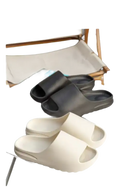 Two pairs of slide sandals, one black and one white.