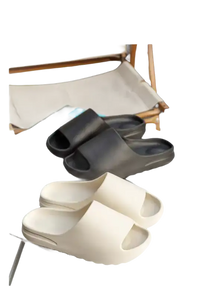 Two pairs of slide sandals, one black and one white.
