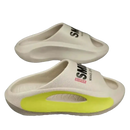 Cream-colored slide sandals with neon yellow accents.