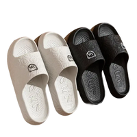 Four cartoon-decorated, black and white, indoor slide sandals.