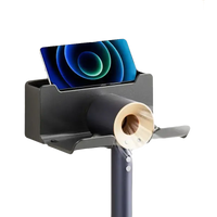 Wall-mounted hair dryer holder with phone slot.