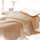 Beige blanket on a bed.