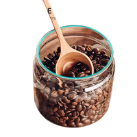 Coffee beans in a glass jar with a wooden spoon.