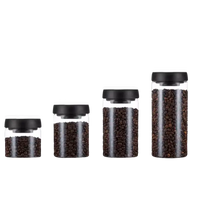 Four glass storage jars with black lids.