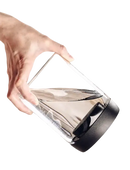 Tilted glass container with black lid and water.