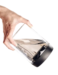 Tilted glass container with black lid and water.