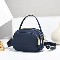 Navy blue nylon crossbody bag with gold zippers.