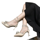 Beige high-heeled shoes with rhinestone straps and bow.