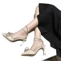 Beige high-heeled shoes with rhinestone straps and bow.