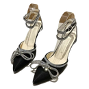 Black high-heeled shoes with rhinestone bows and ankle straps.