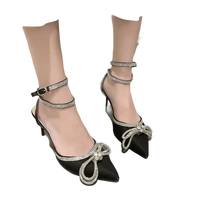 Black high heels with rhinestone bows and ankle straps.