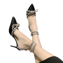 Black high heels with rhinestone bows and ankle straps.