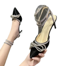Black high-heeled shoe with rhinestone bow and ankle straps.