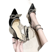 Black stiletto heels with rhinestone bows and straps.