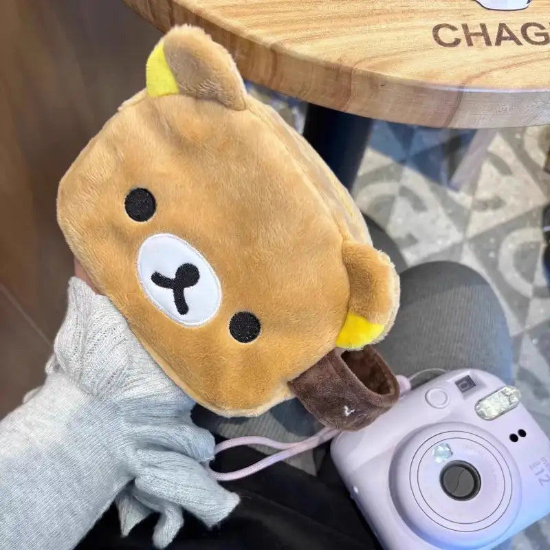 Brown plush bear pouch with camera.