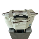 Beige tote bag on suitcase.