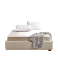 Beige upholstered bed with white pillows.