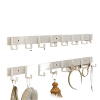 White wall-mounted coat rack with eight hooks.
