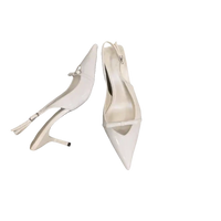 Pair of white, pointed-toe slingback heels.