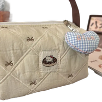 Quilted cream-colored handbag with Hello Kitty donut patch and blue gingham heart charm.