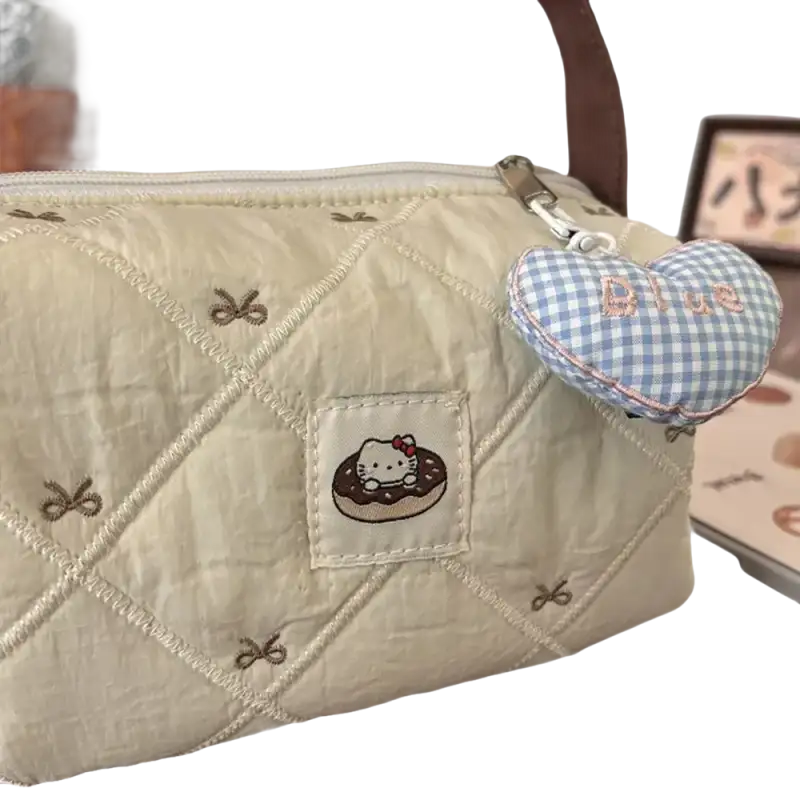 Quilted cream-colored handbag with Hello Kitty donut patch and blue gingham heart charm.