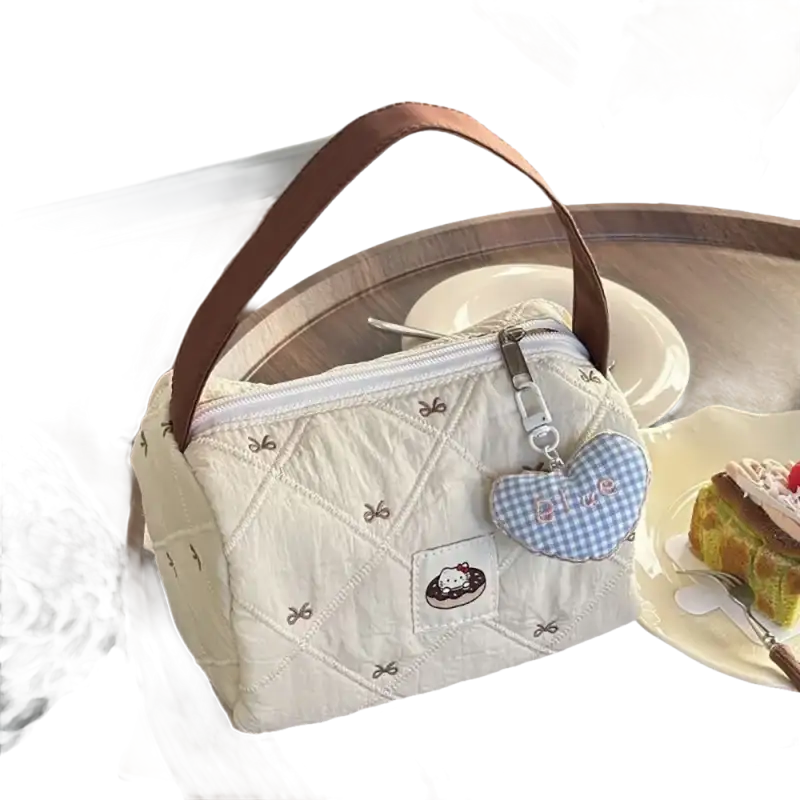 Quilted cream-colored handbag with brown handle and heart-shaped charm.