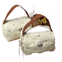 Two quilted handbags with brown handles.