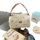 Quilted cream-colored handbag with brown handle.