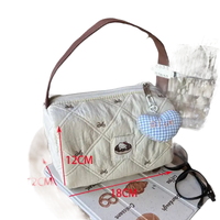 Quilted handbag with brown handle and heart charm.