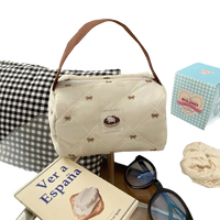 Quilted cream-colored handbag with brown handle.