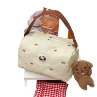 Quilted cream-colored handbag with brown handle and dog keychain.