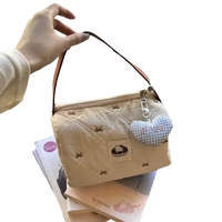 Quilted beige handbag with heart charm.