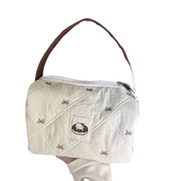 Quilted white handbag with brown strap.