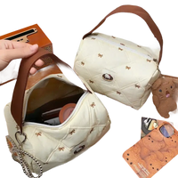 Quilted cream-colored handbag with brown handle.