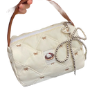 Quilted cream-colored handbag with brown handle and beaded bow.