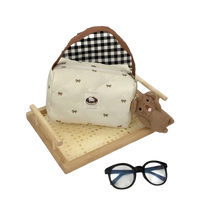 Cream-colored quilted handbag with bow pattern.