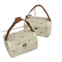 Two quilted, cream-colored handbags with brown handles.