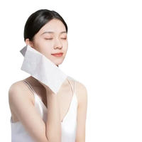 Woman holding a white facial wipe.