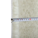 Fluffy white rug with measuring tape.