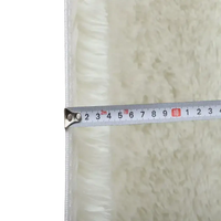 Fluffy white rug with measuring tape.